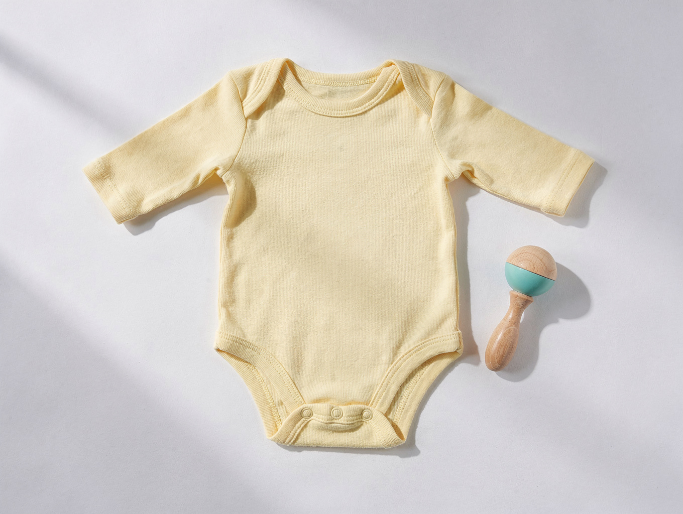 Soft ribbed organic cotton baby onesies folded on a light wood surface